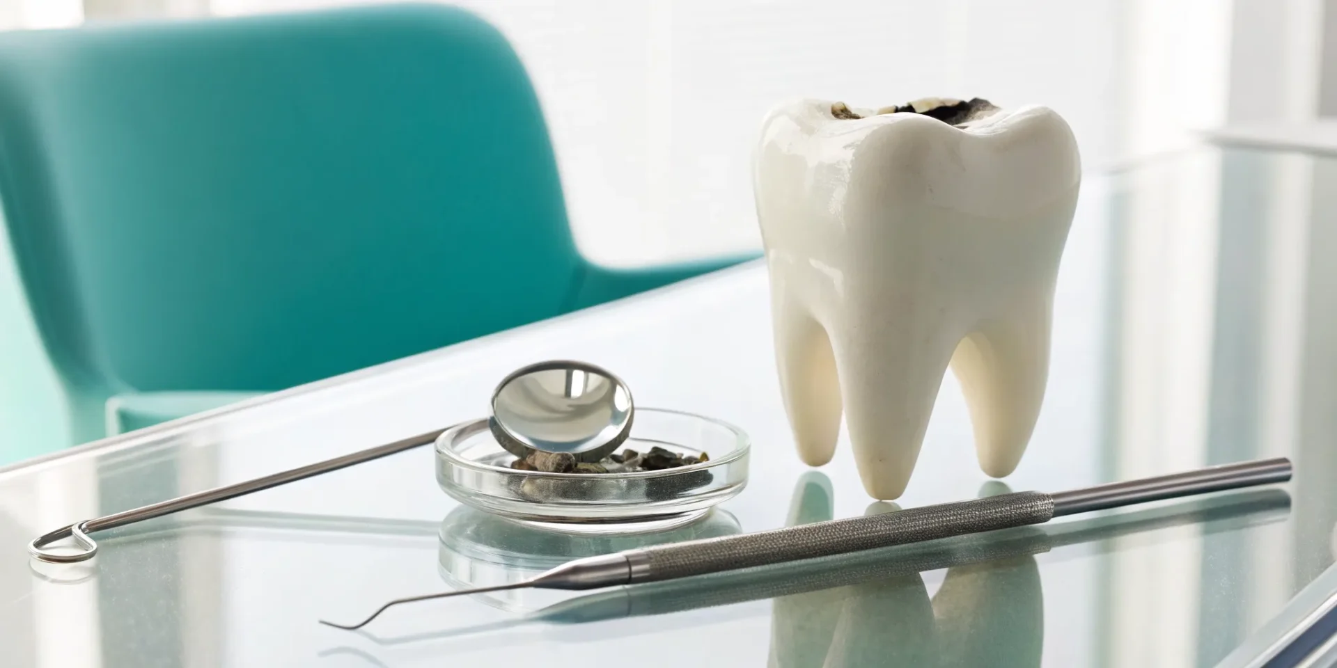 A model of a lost filling and a broken tooth next to dental tools.